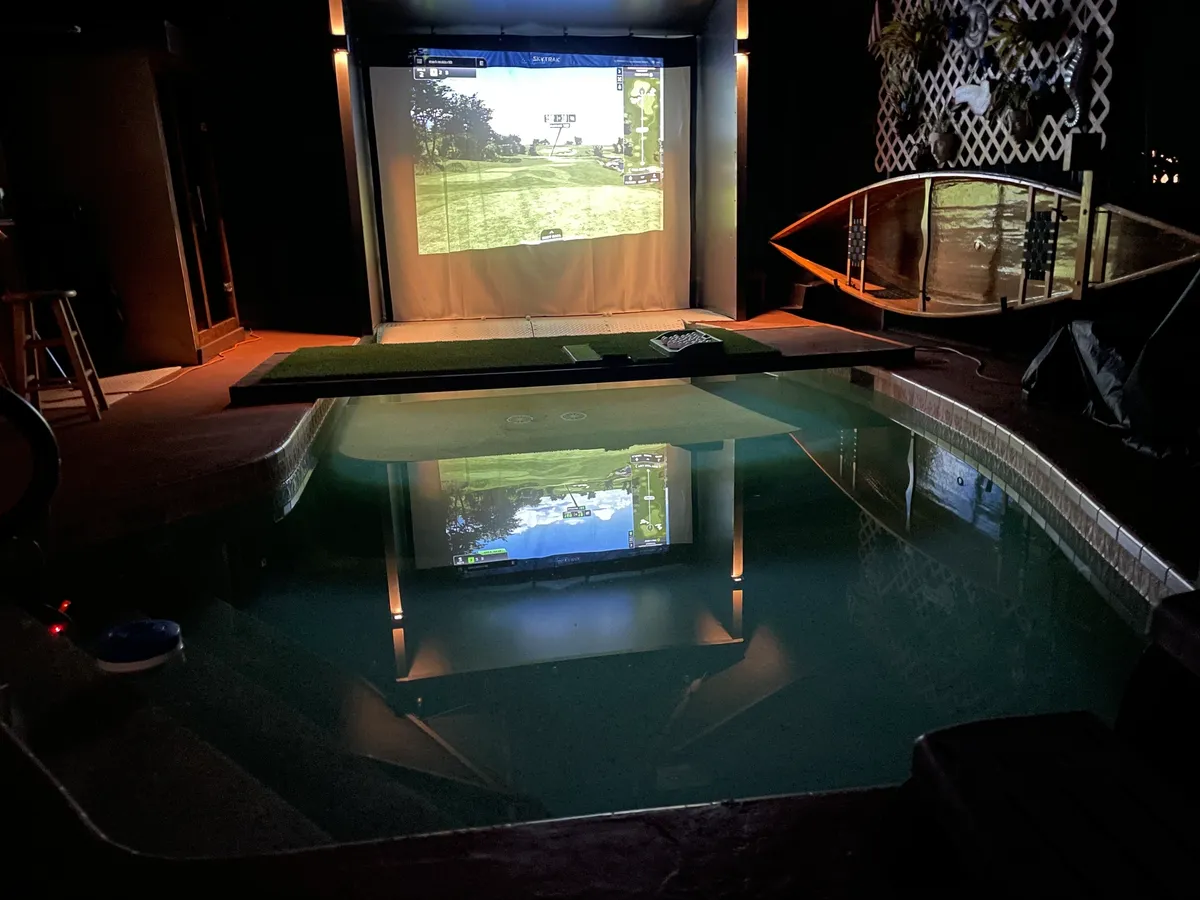 Indoor pool with golf simulator and screen.