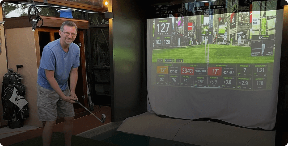 Man playing golf with a simulator indoors.