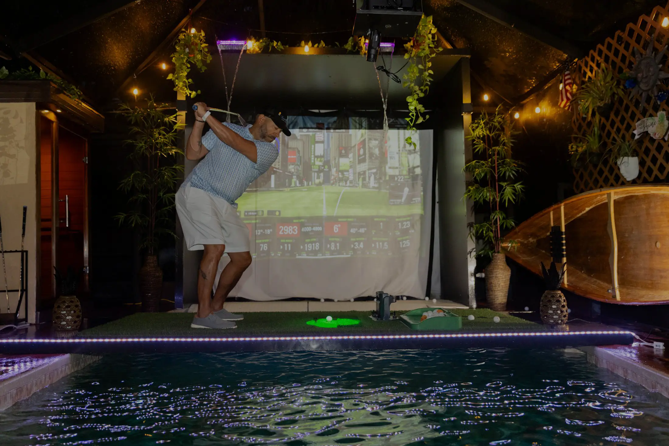 Man playing indoor golf near pool.