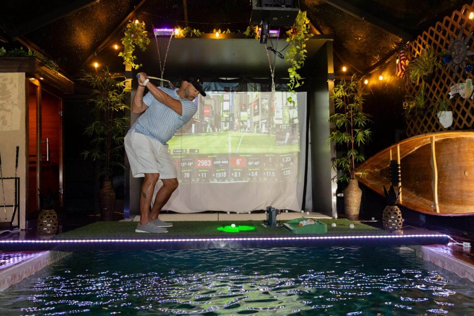 Man playing indoor golf near pool.
