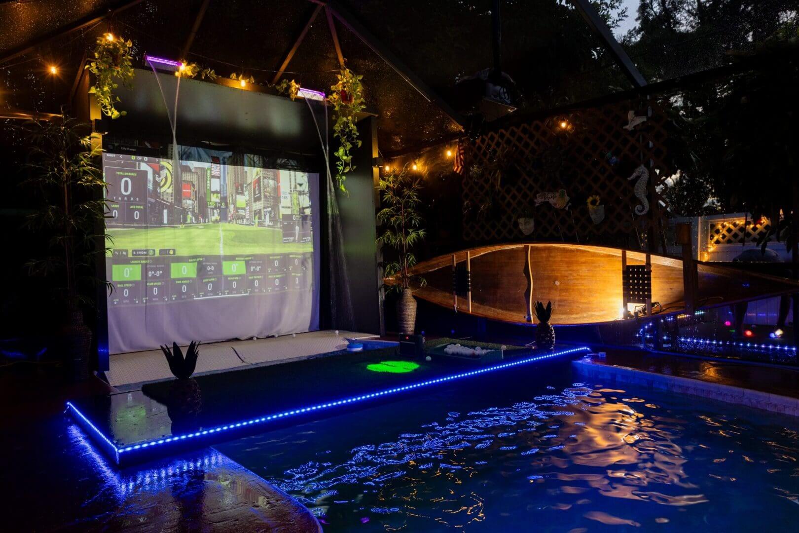 Outdoor poolside movie screen at night.