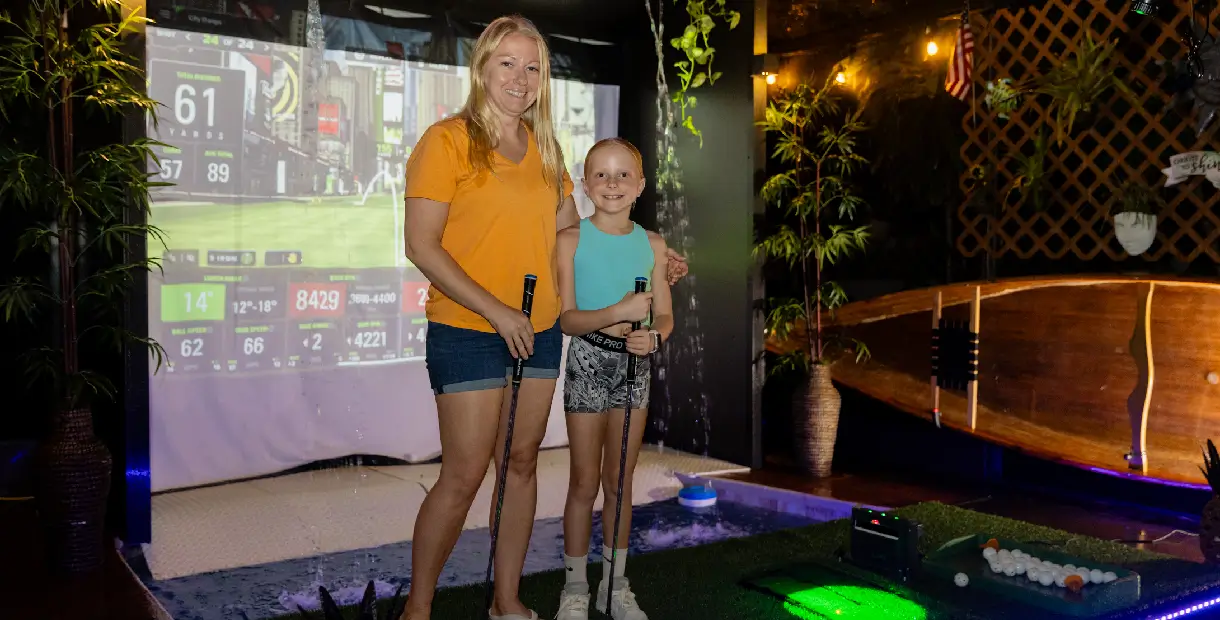Two people playing indoor mini-golf game.